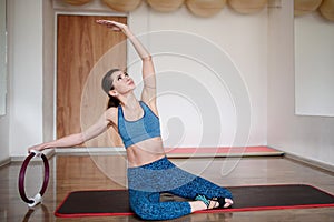 Fit woman in sportswear exercising with a pilates ring in the gym. Copy space