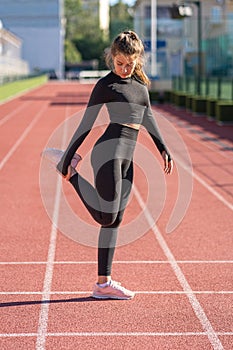 Fit woman in sportswear stretching muscles making functional training, doing exercises for legs, hamstring stretch before jogging