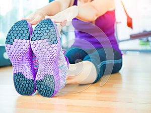 Fit woman stretching her leg to warm up in gym room