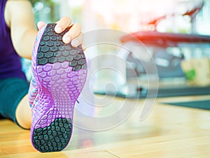 Fit woman stretching her leg to warm up in gym room