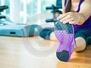 Fit woman stretching her leg to warm up in gym room