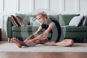 Fit woman stretching at home Forward bend.