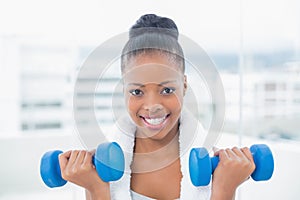 Fit woman with towel around her neck working out with dumbbell