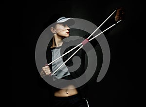 Fit woman training with resistance band against black background