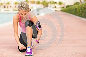 Fit woman tying sports shoe before morning exercise