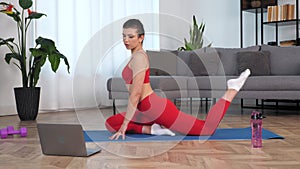 Fit woman watch online sport webinar laptop, doing warm-up stretching training