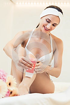 Fit woman waxing her legs with a portable roll-on depilatory wax