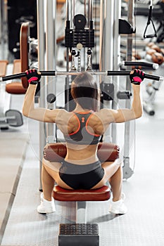 Fit woman working at the lat pulldown machine in the gym. Sport, fitness, powerlifting and people concept.