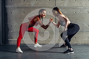 Fit woman wrestle on hands with a female opponent looking in her eyes.