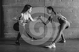 Fit woman wrestle on hands with a female opponent looking in her eyes.