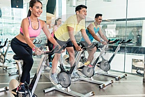Fit women burning calories during indoor cycling class in a fitness club