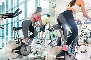 Fit women burning calories during indoor cycling class in a mode