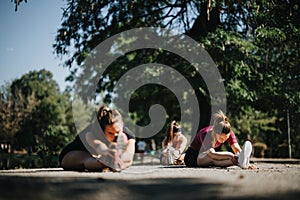 Fit women enjoying outdoor sports and activities in a city park. Stretching and warming up before their workout, they