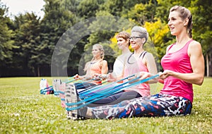 Fit women exercise with blue rubber band in park