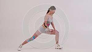 Fit women with kinesiotaping on her body doing fitness and stretching. Health and fitness concept.