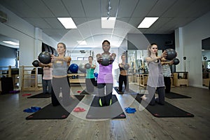 Fit women performing stretching exercise with fitness ball in gym