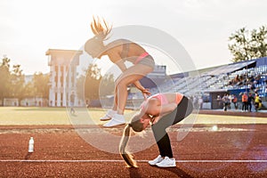 Fit women at the stadium playing leap frog.