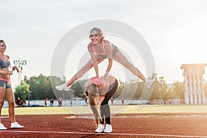 Fit women at the stadium playing leap frog.