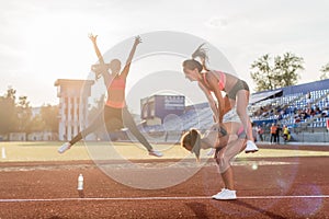 Fit women at the stadium playing leap frog.