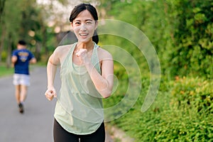 Fit Asian young woman jogging in park smiling happy running and enjoying a healthy outdoor lifestyle. Female jogger. Fitness