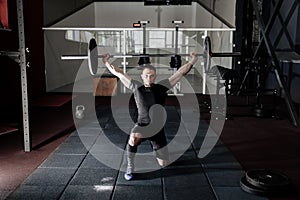 Fit young  athlete lifting the barbell in gym. Gym training. Full body length portrait.