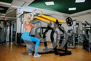 Fit young blonde woman working at the lat pulldown machine in the gym.