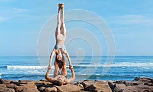Fit young couple doing acro yoga exercise at sea beach