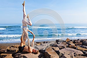 Fit young couple doing acro yoga exercise at sea beach