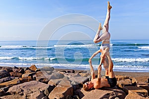 Fit young couple doing acro yoga exercise at sea beach