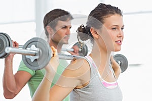 Fit young couple lifting barbells