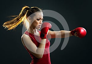 Fit, young, energetic woman boxing, black background