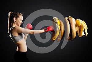 Fit, young, energetic woman boxing unhealthy food