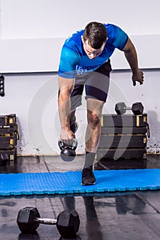 Fit young man doing kettle bell exercise at the gym