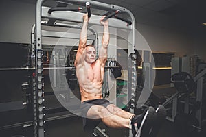 Fit young man doing leg raises on a pull up bar