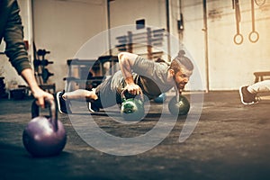 Fit young man planking with dumbbells at the gym photo