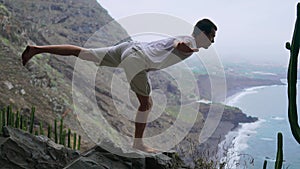 Fit young man practices sun salutation yoga in mountain for ocean. Young man enjoying meditation and yoga. fitness