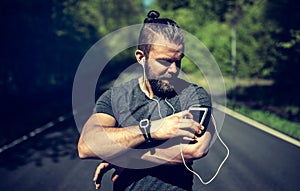Fit young man queueing up his playlist before a run