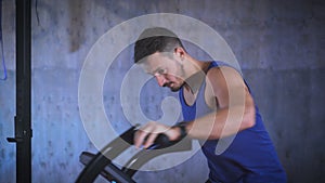 Fit young man using air bike for cardio workout at the gym.