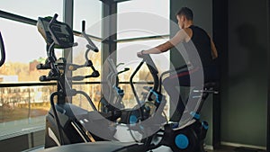 Fit young men using air bike at the gym. Strong male athlete doing cardio workout on cycle at health club.