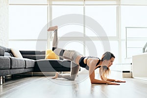 Adult Woman Training Legs and Back Doing Plank Donkey Kicks photo