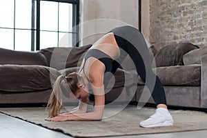 Fit young sportswoman doing standing straddle forward bend or Prasarita Padottanasana pose. Female athlete practicing photo
