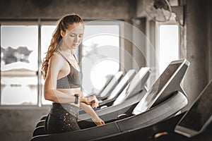 Fit young woman caucasian running on machine treadmill workout in gym. Glad smiling girl is enjoy with her training process.