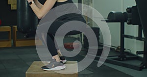 Fit young woman is concentrated on wooden box jumps during sports training in loft gym. People, healthy activity and