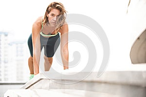 Fit young woman doing plank exercise outdoor in urban environment.