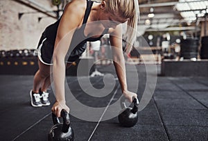 Fit young woman doing pushups with weights in a gym
