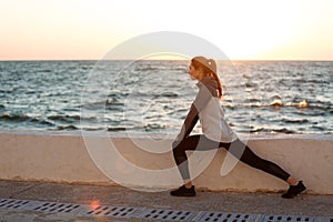 Fit young woman doing stretching workout at the seaside