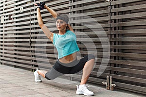 Fit young woman doing yoga stretching exercise, low lunge asana Anjaneyasana pose, outdoors.