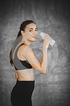 Fit young woman drinking milk from the bottle after exercise in gym. Beautiful woman at gym