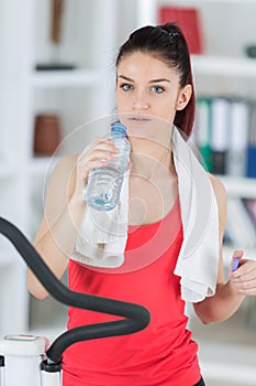 Fit young woman drinking water after step exercise