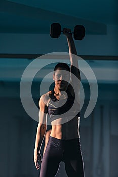 A fit young woman exercising with a dumbbell